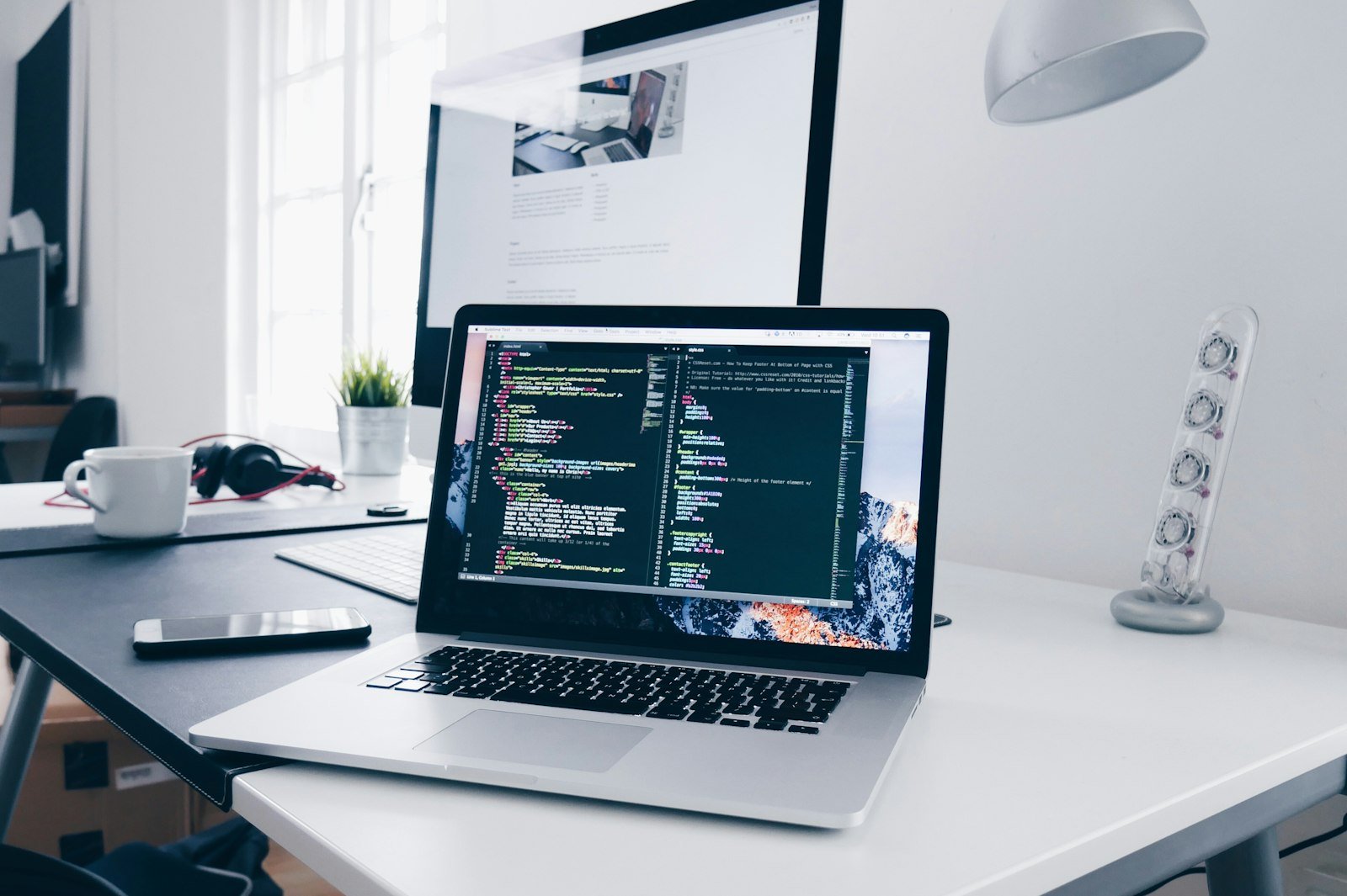 Portatile con il lavoro sul sito. Sul monitor dietro è aperta una pagina.
